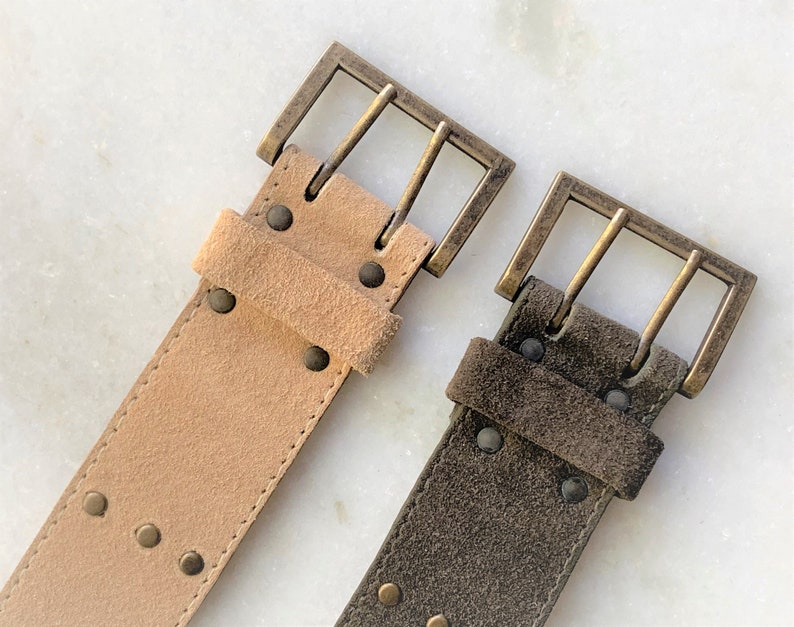 May include: Two suede belts with brass buckles. One belt is light brown and the other is dark brown.