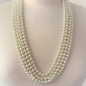 May include: A multi-strand pearl necklace with a classic design. The necklace is made of white faux pearls and is perfect for adding a touch of elegance to any outfit.
