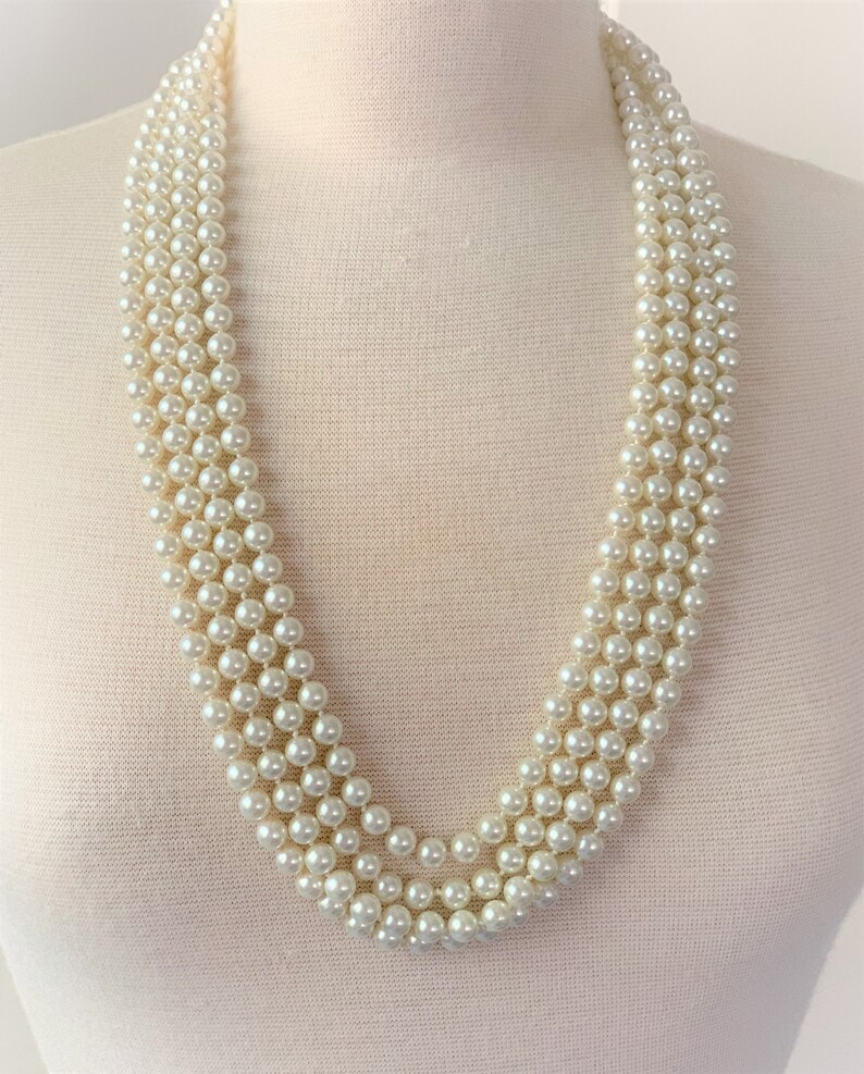 May include: A multi-strand pearl necklace with a classic design. The necklace is made of white faux pearls and is perfect for adding a touch of elegance to any outfit.