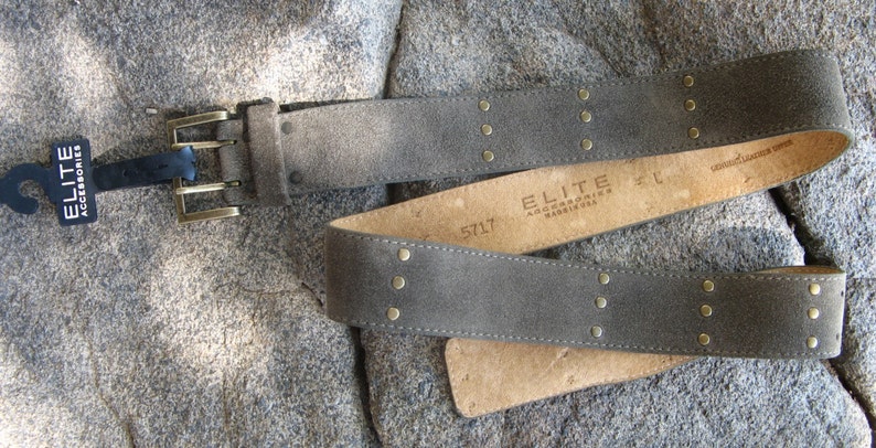 May include: A gray suede belt with gold-toned studs and a double-prong buckle. The belt is labeled "ELITE ACCESSORIES" and "5717".