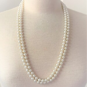 May include: A white pearl necklace with multiple strands. The necklace is on a white mannequin.