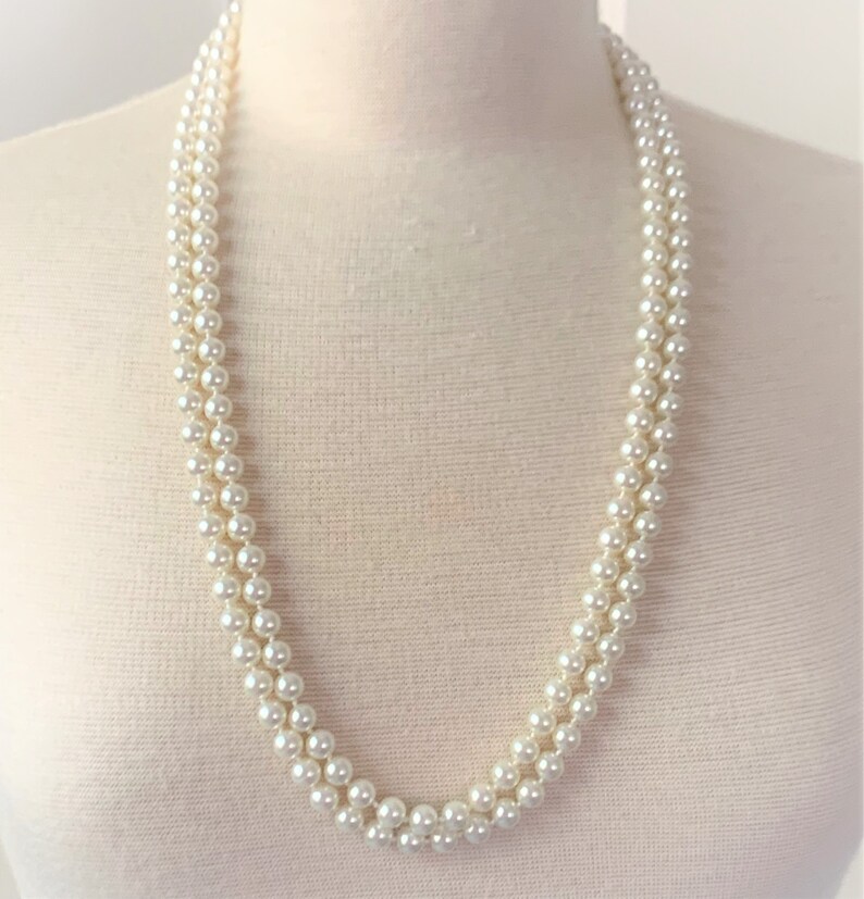 May include: A white pearl necklace with multiple strands. The necklace is on a white mannequin.