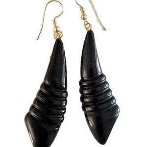 May include: A pair of black earrings with a carved, tapered design. The earrings have gold-colored ear wires. The lower portion of each earring features a series of horizontal ridges, adding texture to the otherwise smooth, glossy surface.