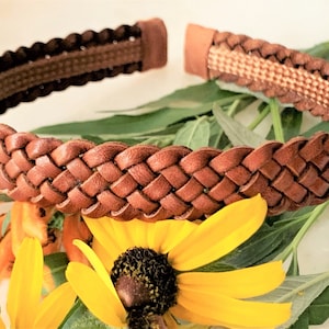 Peut inclure: Un serre-t&ecirc;te en cuir marron avec un motif tress&eacute;. Le serre-t&ecirc;te est sur une surface blanche avec des fleurs jaunes.