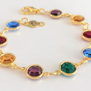 May include: A gold chain bracelet with colorful round gemstones. The gemstones are purple, blue, orange, red, and green.