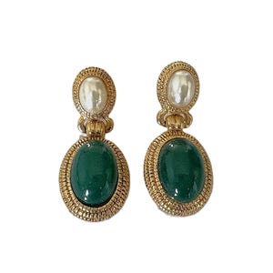 May include: A pair of gold tone earrings with green oval stones and white pearl accents.