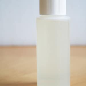 以下が含まれることがあります： 白いプラスチック製のキャップが付いた透明なガラス瓶。瓶には透明な液体が入っています。