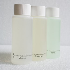 以下が含まれることがあります： 白いキャップとラベルが付いた透明なガラス瓶が3本。ラベルには「Ethereal」、「Embody」、「Iconic」の文字が書かれています。