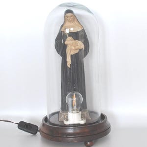 Plaster statue depicting Saint Rita of Cascia with wooden base and glass dome