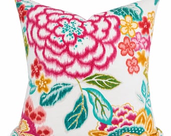May include: A square throw pillow featuring a white background with a vibrant floral pattern. The design includes large magenta peonies, smaller yellow and pink blossoms, and teal green leaves, all rendered in a painterly, watercolor-like style.