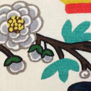 May include: A white fabric with a floral pattern. The flowers are white with yellow centers and green leaves. The background is a light cream color.
