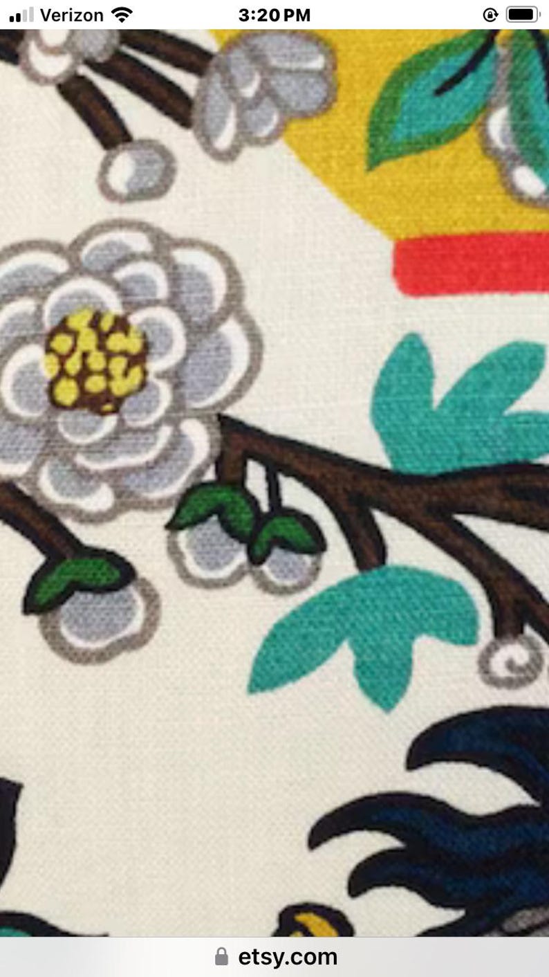 May include: A white fabric with a floral pattern. The flowers are white with yellow centers and green leaves. The background is a light cream color.