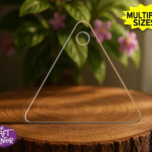 May include: A clear, triangular craft template with a circular handle. The template is displayed on a wooden surface, with the text "MULTIPLE SIZES!" in a yellow starburst and "Mini Craft Corner" in a purple circle.