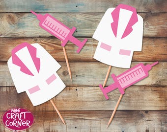 May include: Pink and white doctor-themed paper cutouts on wooden skewers. The cutouts include a syringe and a doctor's coat. The Mini Craft Corner logo is visible in the lower left corner.