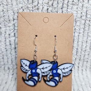 May include: A pair of blue and white bee earrings with silver hooks. The bees are wearing blue jerseys with a white number "8" on the front.