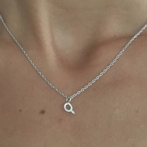 May include: A silver chain necklace with a small silver letter Q pendant.