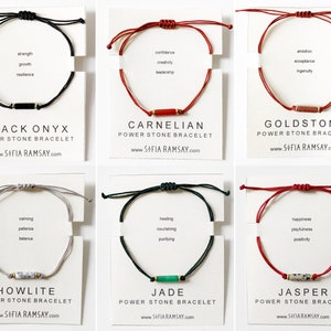May include: Six different coloured string bracelets with a small stone bead in the centre. Each bracelet is labelled with the name of the stone and a list of its associated qualities. The stones are Black Onyx, Carnelian, Goldstone, Howlite, Jade, and Jasper.