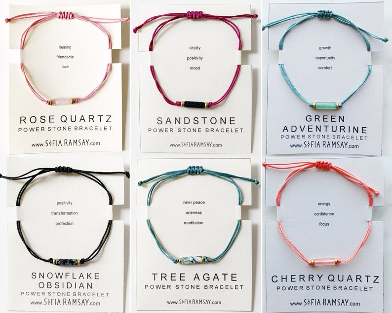 May include: Six different coloured string bracelets with a single stone bead in the centre. The bracelets are labelled with the stone name and the words "Power Stone Bracelet". The website address "www.SOFIA RAMSAY.com" is printed below each bracelet.