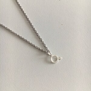 May include: A silver chain necklace with a small silver pendant in the shape of the male symbol.