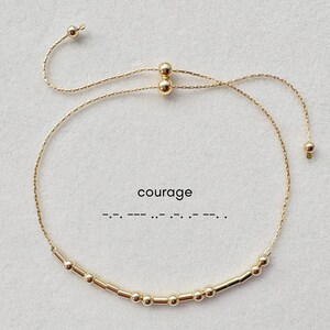 May include: A gold adjustable bracelet with a series of small gold beads and the word "courage" written in braille.