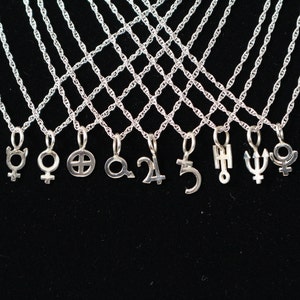 May include: A set of silver necklaces with various celestial symbols as pendants, including the symbols for Venus, Mars, Saturn, Jupiter, Uranus, Neptune, and Pluto.