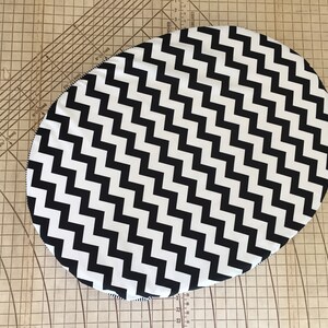 May include: Black and white chevron patterned oval fabric cushion.