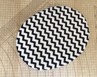 May include: Black and white chevron patterned oval fabric cushion.