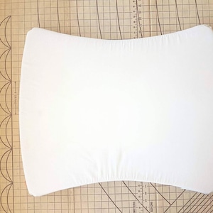 May include: White fitted cot sheet with a curved shape. The sheet is made of a soft, breathable fabric.
