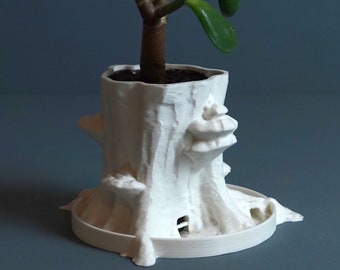 May include: White ceramic planter shaped like a tree stump with a small green succulent plant growing out of the top.