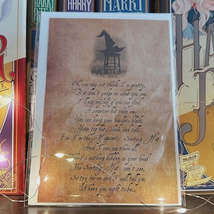 May include: A vintage-style card with a parchment background and a black and white illustration of a wizard's hat. The card features a poem about the Sorting Hat from the Harry Potter series. The poem reads: "Oh, you may not think I'm pretty, But don't judge on what you see, I'll eat myself if you can find A smarter hat than me. You can keep your bowlers black, Your top hats, sleek and tall, For I'm the Hogwarts Sorting Hat And I can cap them all. There's nothing hidden in your head The Sorting Hat can't see, So try me on and I will tell you Where you ought to be..."