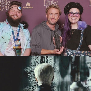 May include: A photo of three people, two men and one woman, standing in front of a purple backdrop. The man in the middle is holding a dark gray award. The woman is wearing a purple and white dress with a black and white pattern. The man on the left is wearing a blue and white patterned shirt. The text "Leaky Con" is visible in the background.