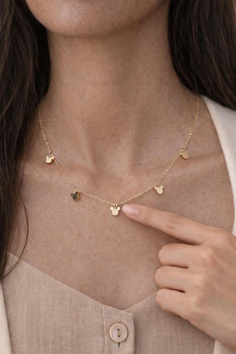 Puede incluir: Un delicado collar dorado con m&uacute;ltiples dijes peque&ntilde;os con forma de cabeza de Mickey Mouse. El collar se lleva alrededor del cuello y es un accesorio sencillo pero encantador. Un gran regalo para los fans de Disney.