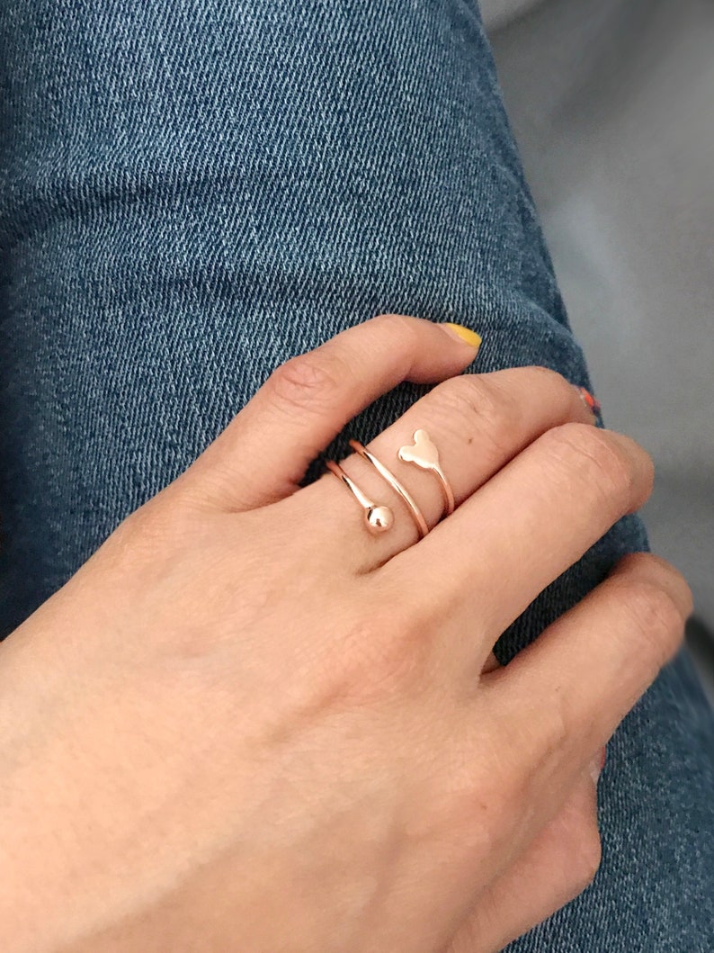 K&ouml;nnte beinhalten: Ein Ring aus Ros&eacute;gold mit einem herzf&ouml;rmigen Design und einer kleinen Kugel am Ende des Bandes.
