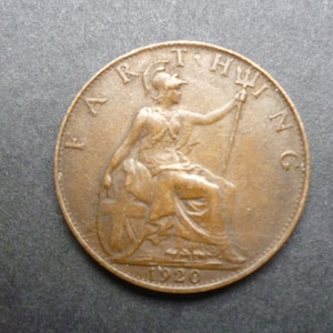 May include: A copper-colored British farthing coin with the inscription "FARTHING" and the year "1920" on the reverse side.