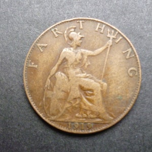 Könnte beinhalten: Eine kupferfarbene britische Farthing-Münze aus dem Jahr 1919, die eine sitzende Figur von Britannia mit einem Dreizack und einem Schild zeigt, mit der Inschrift "FARTHING" am Rand.