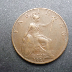Könnte beinhalten: Eine kupferfarbene britische Farthing-Münze mit der Aufschrift "FARTHING" und dem Jahr "1921".