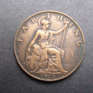 Könnte beinhalten: Eine kupferfarbene britische Farthing-Münze mit der Inschrift "FARTHING" am Rand und dem Jahr "1923" unten. Die Münze zeigt eine sitzende Figur von Britannia, die einen Dreizack hält.