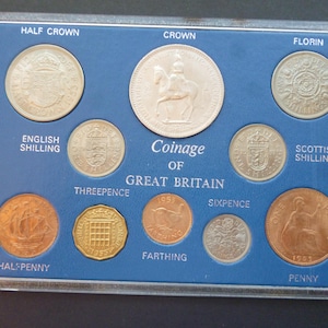 Op de afbeelding: Een 1953 Coinage of Great Britain set in een doorzichtige plastic houder. De collectie bevat een Half Crown, Crown, Florin, English Shilling, Scottish Shilling, Threepence, Farthing, Sixpence, Halfpenny en een Penny, allemaal voorzien van labels.