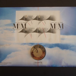 May include: A white envelope with a gold coin and four stamps. The stamps feature a map of the world and the text "LAST DAY OF 1999 MM 31.12.99 GREENWICH LONDON" and "FIRST DAY OF 2000 MM 01.01.00 GREENWICH LONDON". The coin is gold and features the text "2000 ANNO DOMINI".