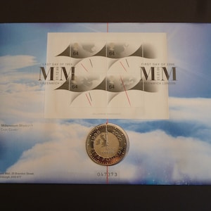 May include: A coin cover featuring a commemorative coin with the text "1999 2000 Anno Domini Five Pounds" and a depiction of the Millennium Dome. The cover also features four stamps with the text "Last Day of 1999 MM Greenwich London" and "First Day of 2000 MM Greenwich London".