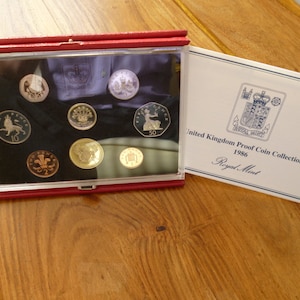 Set di 8 monete Proof 1986 della Royal Mint del Regno Unito, custodite in un astuccio imbottito in pelle rossa della Royal Mint con foglietto illustrativo. Set di monete Proof inglesi del 1986.