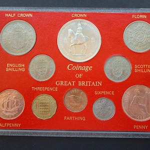 Op de afbeelding: Een 1953 Coinage of Great Britain muntenverzameling in een doorzichtige plastic houder op een rode achtergrond. De set bevat een crown, half crown, florin, Engelse shilling, Schotse shilling, threepence, sixpence, penny, halfpenny en een farthing munt.