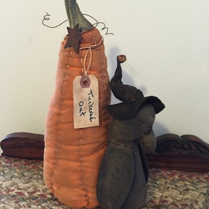 May include: A handmade orange pumpkin with a brown star and a tag that says "Tucked Out" is standing next to a brown fabric elephant with a small brown hat.