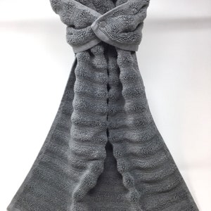 May include: A gray, textured kitchen towel with a button closure. The towel is hanging on a silver bar.