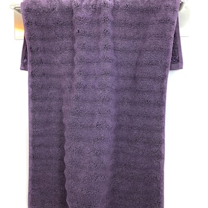 May include: A purple bath towel hanging on a silver towel rack.