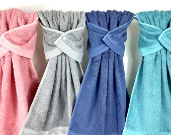 May include: Four bath towels hanging on a rack. The towels are in different colors: pink, gray, blue, and teal.