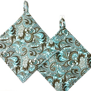 May include: Two teal and brown paisley patterned pot holders with loops for hanging.