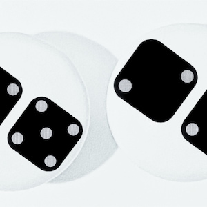 May include: Two white round buttons with black dice printed on them. The dice are in a stacked configuration. The top die has one dot and the bottom die has five dots.