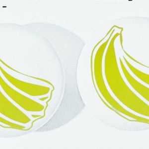 May include: Two white round stickers with a yellow banana graphic on each.