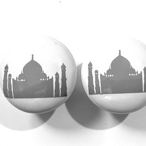 May include: Two white ceramic knobs with a gray silhouette of the Taj Mahal on each.